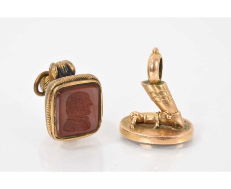 Two antique seals to include a gold seal in the form of an armoured arm holding a shield (lacking intaglio) and a Regency gil