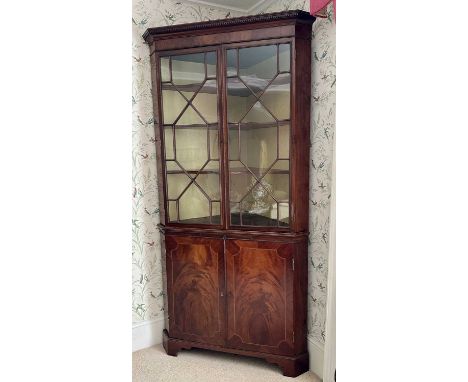 Regency mahogany corner cabinet inlaid with stringing enclosed by a pair of glazed doors above a slide and a pair of cupboard
