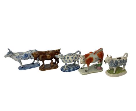 Four 19th century ceramic cow creamers, of various type, and a Delft model of a cow