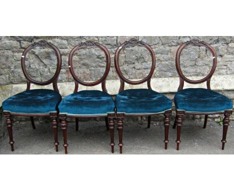 A set of four Victorian mahogany balloonback dining chairs with carved and moulded detail, button upholstered seats and slend