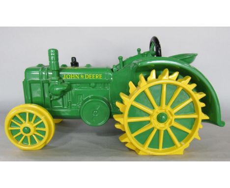 A china storage jar in the form of an early John Deere tractor with a removable steering wheel lid, 42cm x 24cm 