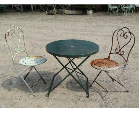 A weathered light steel circular folding garden terrace/bistro table of circular form, 74cm diameter, together with a pair of