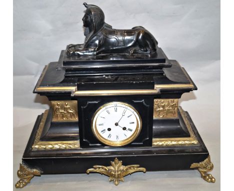 A mid-19th century black slate and polished brass mantle clock with pseudo Egyptian detail surmounted by a sphinx and enclosi