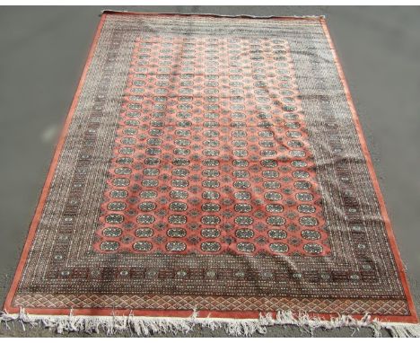 A Turkoman style carpet with many rows of small medallions on a light pink ground, 320cm x 250cm approx 