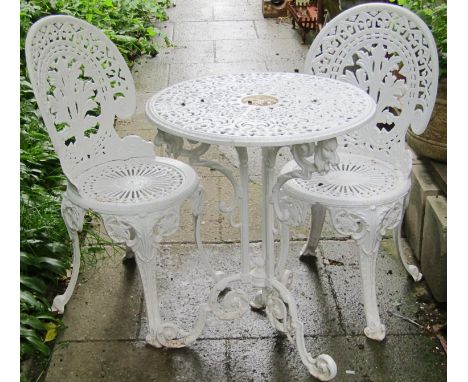 A small cast iron cream painted garden table with decorative pierced circular top with central portrait, raised on scrolled s