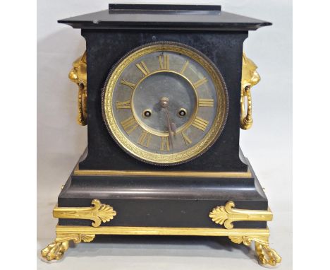 A Victorian black slate and gilded brass overlaid mantle clock with lion mask and ring handles and lions paw feet with eight 