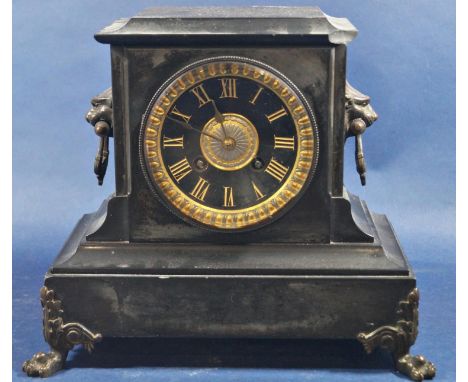 A mid-Victorian black slate mantle clock with eight day striking movement, with lion mask and lions paw mounts 