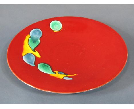 A large decorative Poole Pottery charger with green, blue and yellow highlights on a sang de boeuf ground, 42cm diameter appr