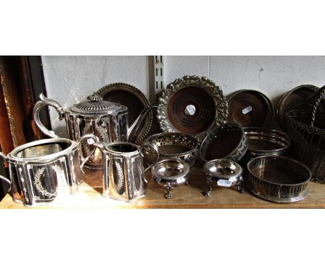 Eight early 20th century silver plated wine coasters, a wine bottle holder, a three piece tea service and two salt cauldrons.