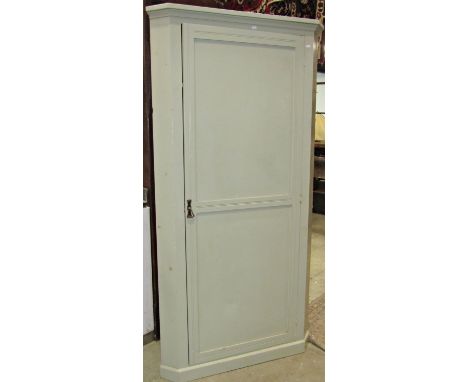 An Edwardian floorstanding corner cupboard with light green painted finish, enclosed by a single twin moulded panelled door w