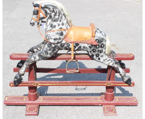 Rocking Horse: A mid-20th century dapple grey wooden rocking horse, upon painted wooden base. Wear to saddle, nibbles to hors