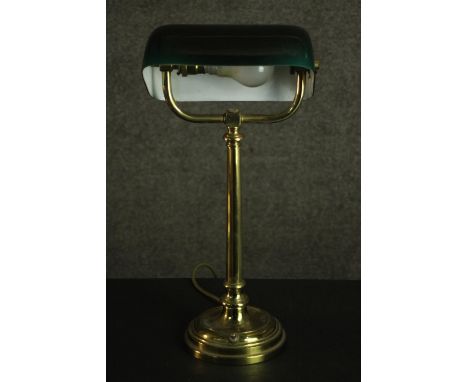 An early 20th century banker's brass desk lamp, with an adjustable green glass shade, on a circular base. H.47 W.23 D.14cm. 