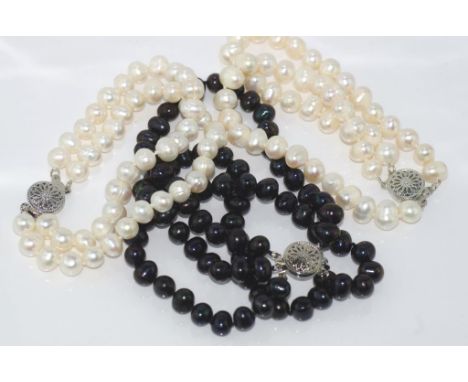 Three multi-strand pearl bracelets two white and one dark blue-black