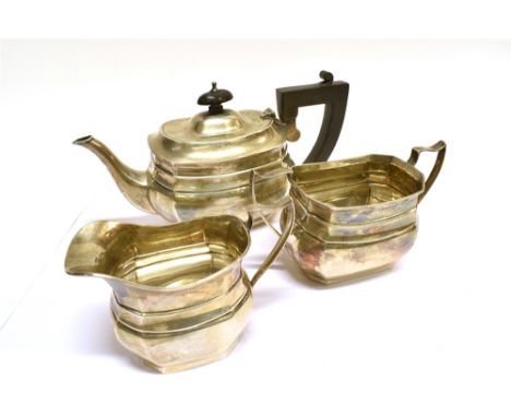 A SILVER SMALL THREE PIECE TEA SERVICE of cut-corner oblong design, the teapot with an ebonised angular-scroll handle and fin