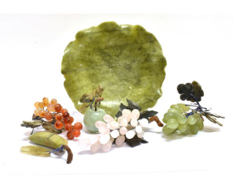 A CARVED GREEN HARDSTONE FRUIT BOWL WITH A WAVY BORDER AND A COLLECTION OF HARDSTONE FRUITS to include; a green apple; a bana