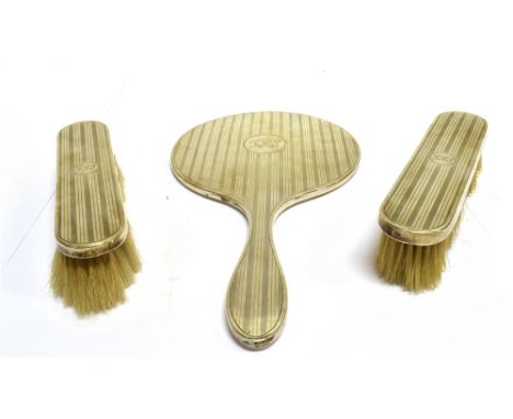A SILVER MOUNTED THREE PIECE DRESSING TABLE SET comprising; a round hand mirror and two oblong clothes brushes, each with eng