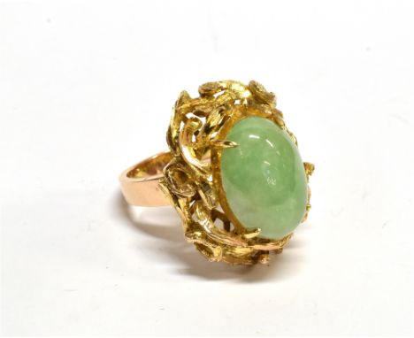 AN ORIENTAL YELLOW METAL AND PALE-GREEN OVAL CABOCHON JADEITE SINGLE STONE RING the slightly mottled pale-green stone approx.