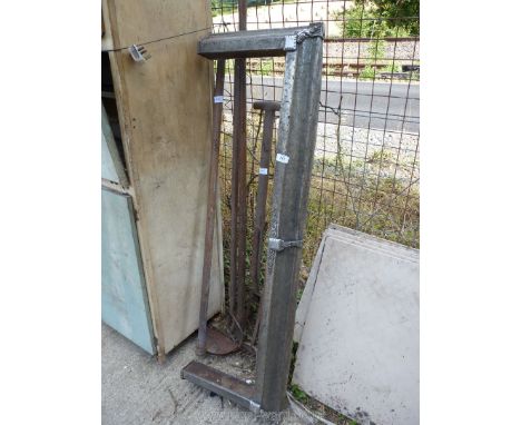 A metal fire surround and garden tools including fork, rake and hoe.