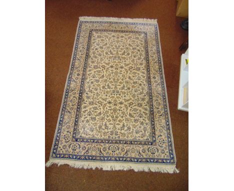 A Persian wool carpet cream ground with repeating floral pattern and blue floral border, 254 x 155cm