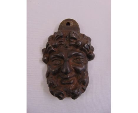 A cast bronze door knocker in the form of a mans bearded visage