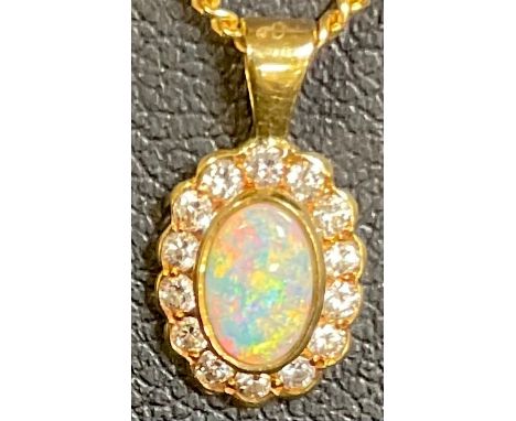 An 18ct gold necklace suspended with an 18ct gold opal polished cabochon pendant, the opal surrounded by fourteen brilliant c