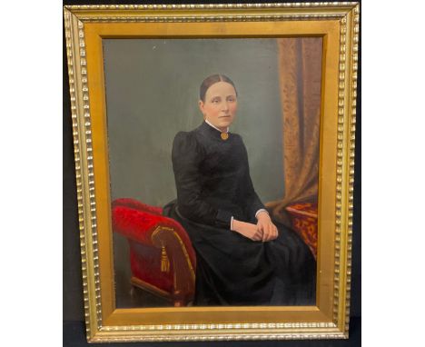 A Victorian overpainted portrait, of a lady seated o a red sofa, wearing a long black dress, 57cm x 43cm, framed 