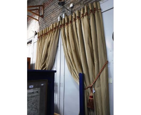 A PAIR OF GOLD SILK AND VELVET CURTAINS, circa 106" drop, gathered width 44", hem width 100" with red and gold braid trim and