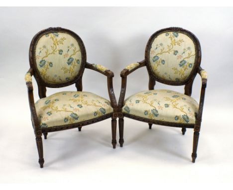 A pair of Louis XVI style beech framed open armchairs, each with oval panel back and overstuffed seat, acanthus carved uprigh