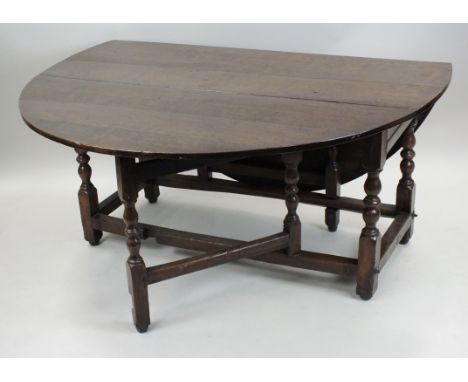 An oak drop leaf dining table, 18th century, the oval planked top above a single end frieze drawer and single gate leg action