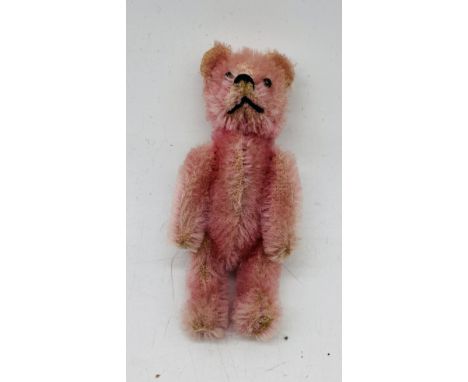 A Schuco miniature pink mohair teddy bear with metal pin eyes and black stitched nose/mouth, head twists - overall height 9cm