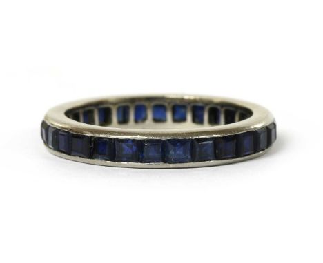 A white gold sapphire full eternity ring, with a row of square step cut sapphires, channel set, to plain polished guards, tes