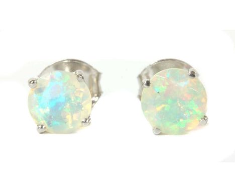 A pair of white gold single stone opal stud earrings, with a circular faceted opal, claw set to post and butterfly fittings, 