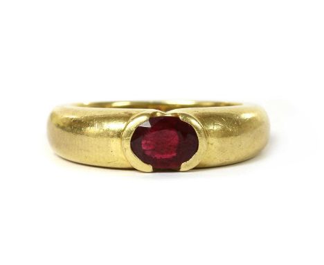 An 18ct gold single stone ruby ring, with an oval mixed cut ruby, semi-rub set, to slightly tapered shoulders and a 'D' secti