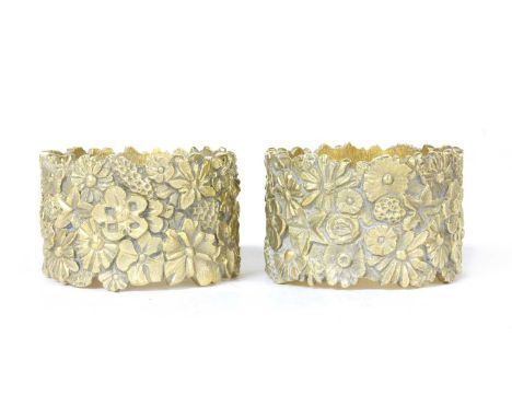 A pair of silver gilt napkin rings, by Stuart Devlin, London 1976, each heavy and cast with flower heads and leaves, 5cm diam
