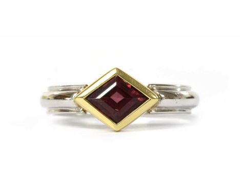 A two colour gold single stone garnet ring, with a lozenge shaped step cut garnet, rub set in yellow gold, to a white gold sh