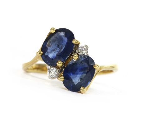 An 18ct gold sapphire and diamond crossover ring, with two oval mixed cut sapphires with a pair of brilliant cut diamonds bet