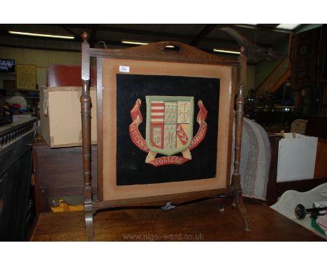 A Fire screen with Queen's College, Cambridge needlework motif, in oak frame.