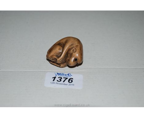 A signed and carved Japanese Fruitwood Netsuke of a Monkey with glass inset eyes.
