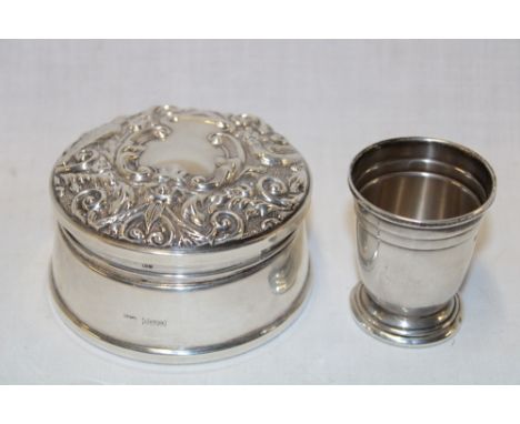 A good quality silver circular ring box with raised scroll decoration and a small silver measuring cup (2)