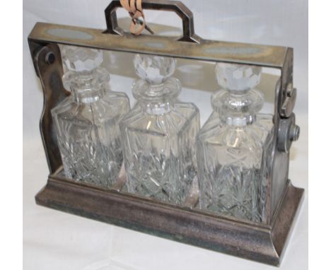 A silver plated three-bottle tantalus with three matching cut glass decanters and key 