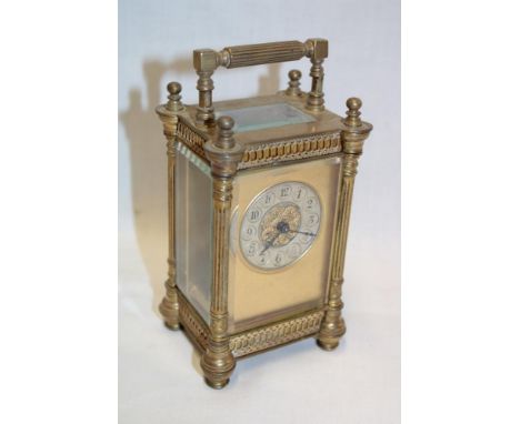 A French carriage clock with silvered circular dial in brass ornamental case 