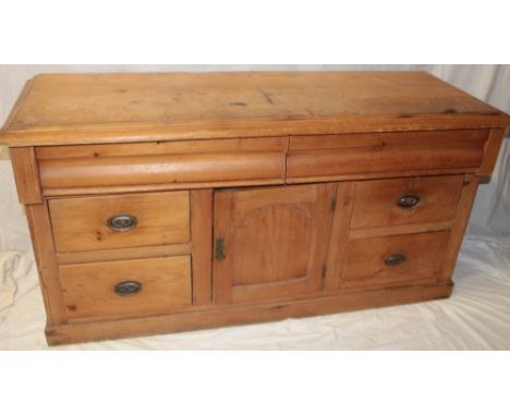 A Victorian pine dresser base/side cabinet with central cupboard enclosed by a panelled door flanked by four small drawers an