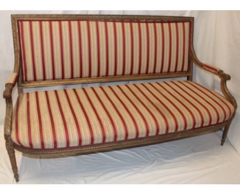 A 19th century French gilt open arm sofa upholstered in striped floral fabric on turned legs, 64" long