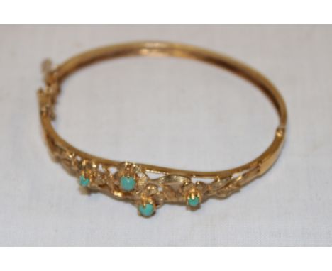 A 9ct gold oval bangle with floral mounts set turquoise (12.4g) 