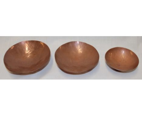 Three Newlyn copper circular graduated pedestal bowls with beaten decoration 5½" diameter to 4" diameter 