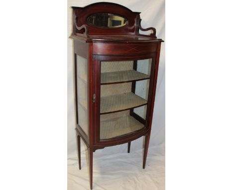 A late Victorian inlaid mahogany bow fronted display cabinet with fabric lined shelves enclosed by a curved panelled door bel