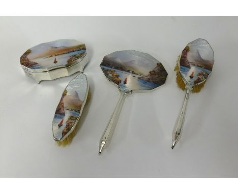 A four piece Geo V silver dressing table set with enamel back depicting a boat, lake and mountain scene, Birmingham 1929, mak