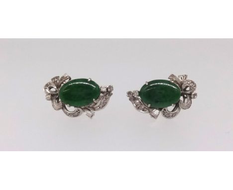 A pair of Nephrite jade and diamond earrings, central oval cut jade, claw set, mounted in all white gold scroll design with s
