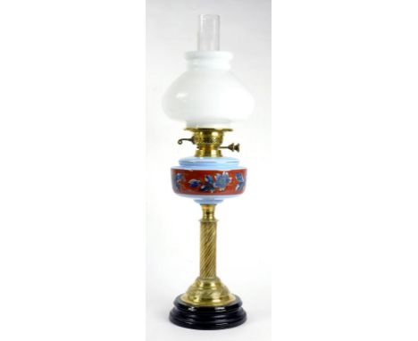 AN EARLY 20TH CENTURY BRASS SPIRAL OIL LAMP, WITH ENAMELLED BLUE GLASS FOUNT AND BRASS DUPLEX BURNER, OPAL SHADE, ON BLACK GL