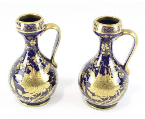 A pair of 19th century Staffordshire glazed ceramic ewers, decorated with gilt foliate motifs on a blue ground, each measurin
